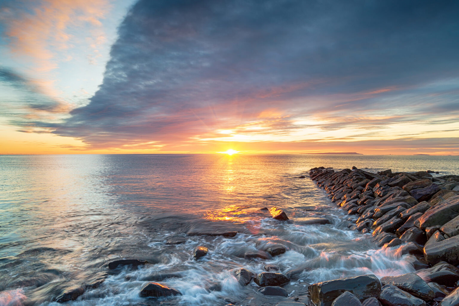 Dramatic winter sunset over a rocky outcrop at Kimmeridge Bay on the Dorset coastline